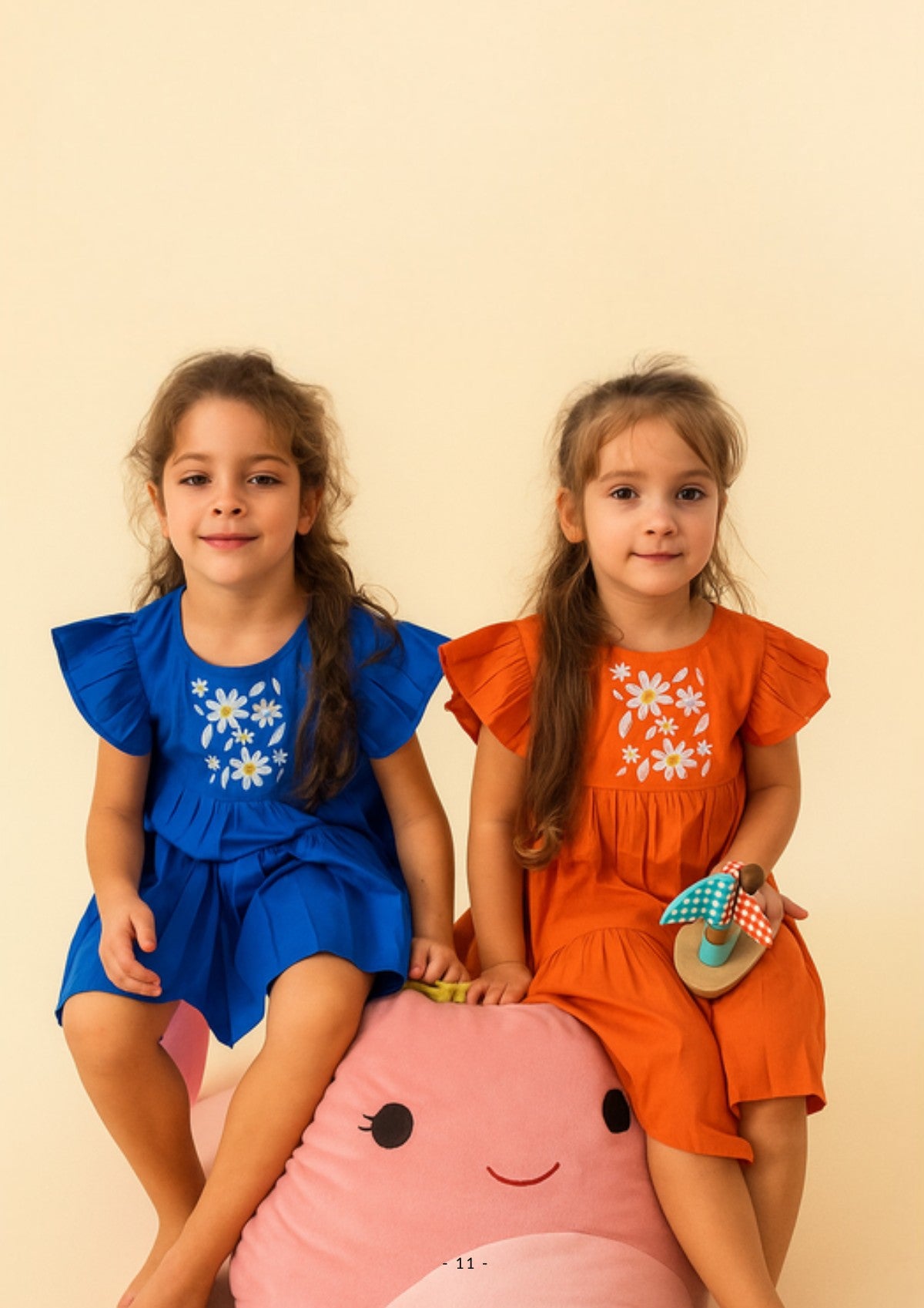 Two girls in Ola! Otter organic cotton embroidered dresses in blue and orange