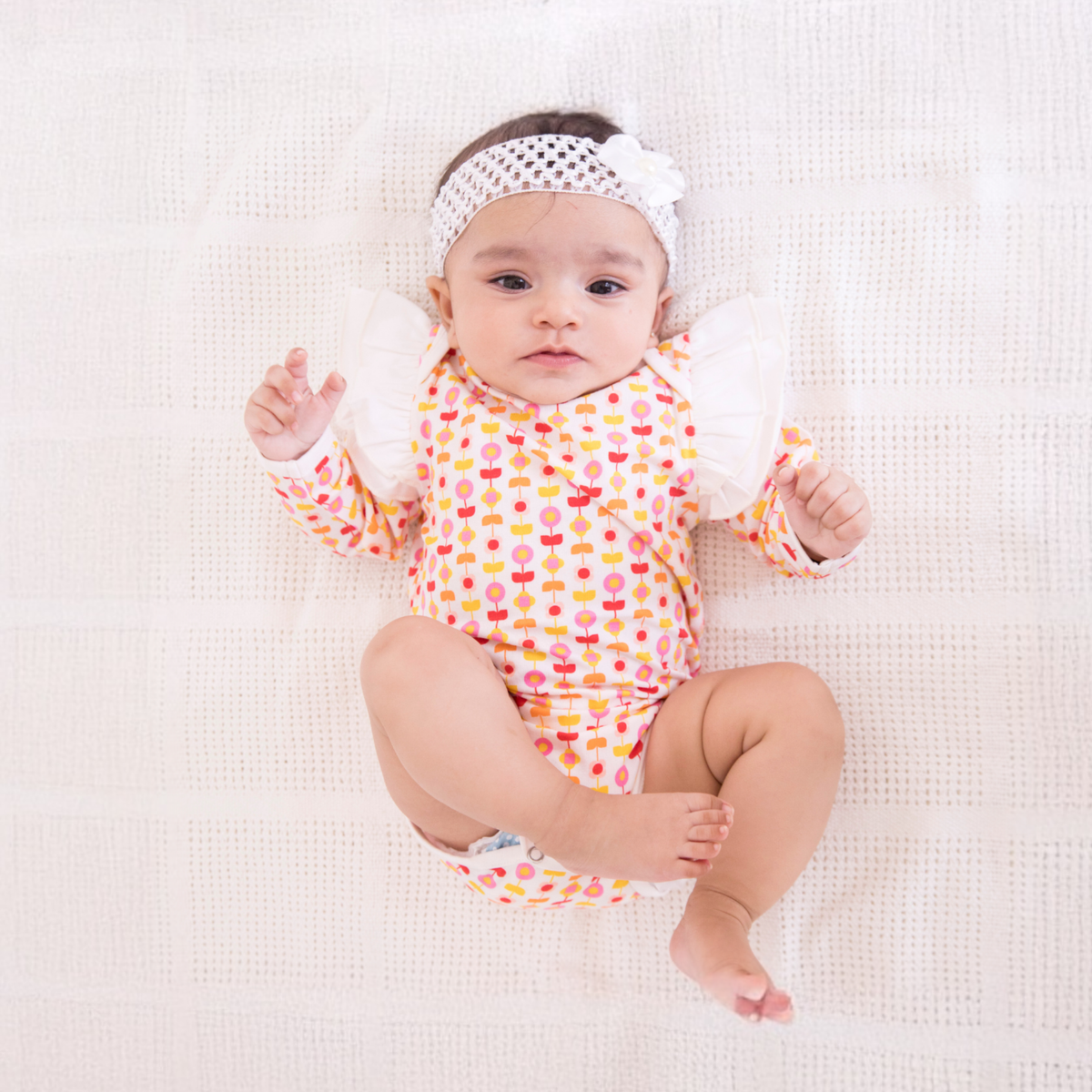 Baby girl sitting in an Ola! Otter organic cotton printed bodysuit