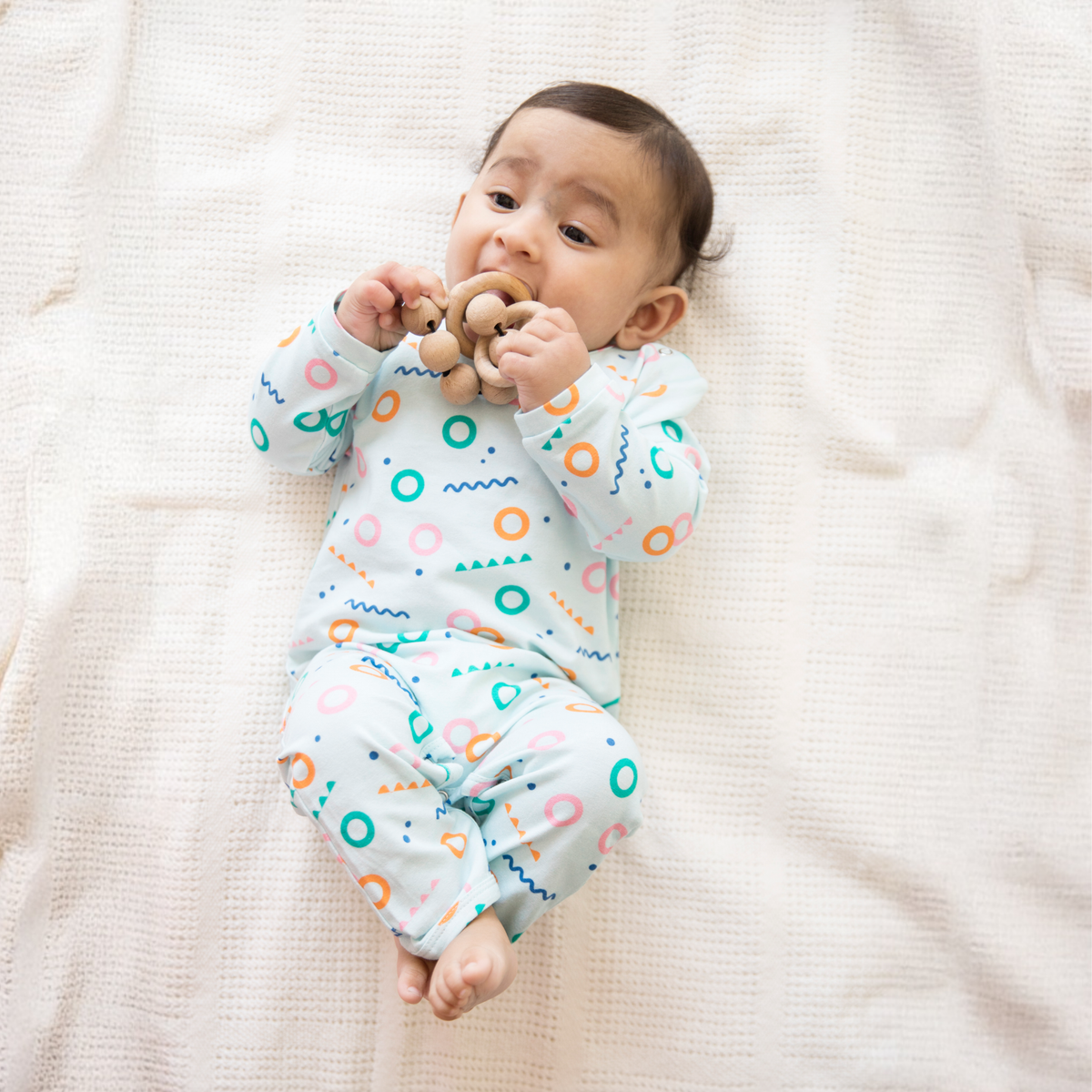 Smiling baby in an Ola! Otter organic cotton footed sleepsuit in a bird print