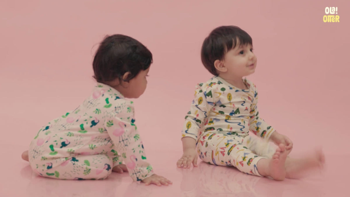 Two babies in Ola! Otter organic cotton sleepsuits